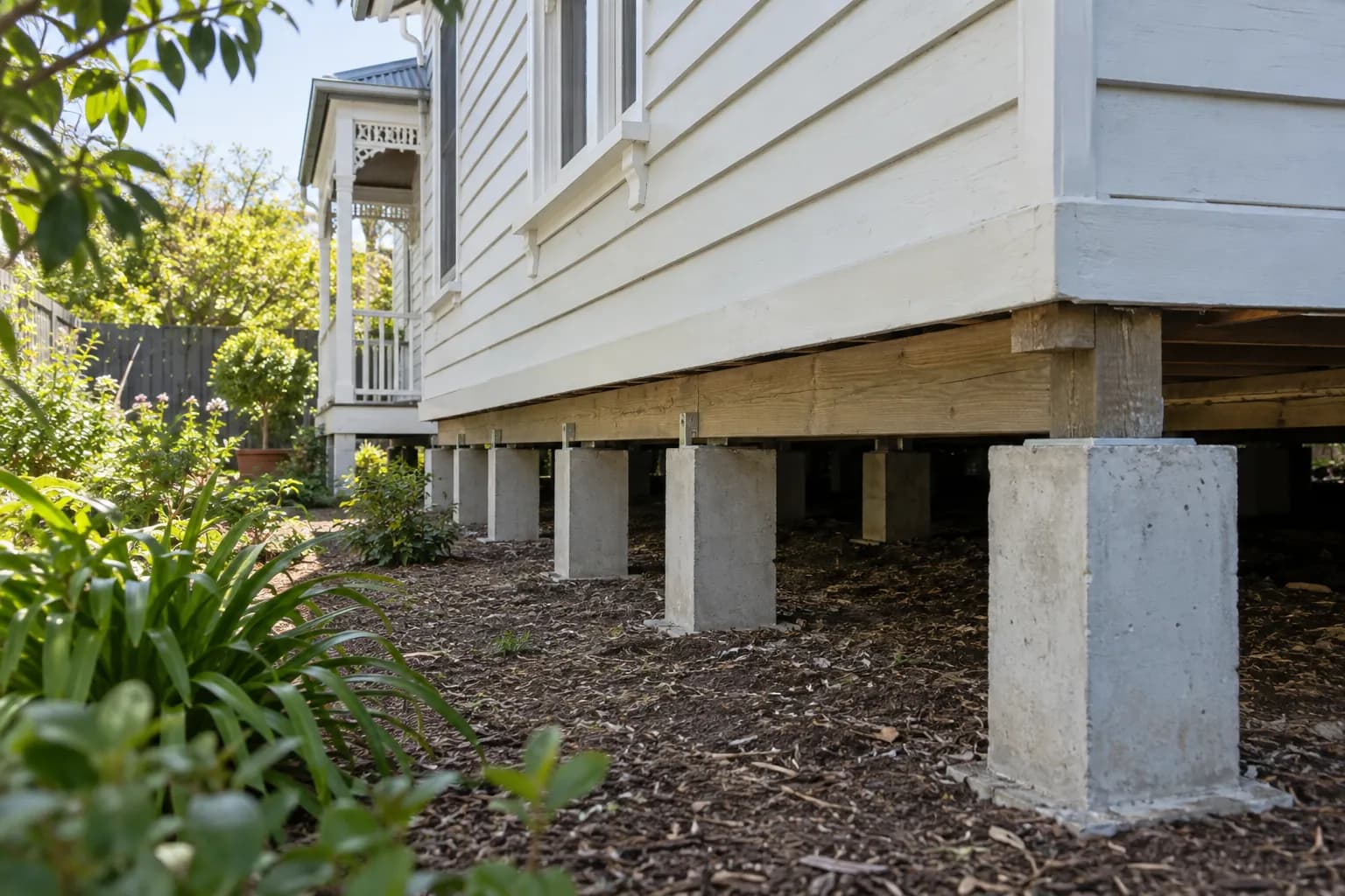 Weatherboard home supported on concrete stumps beside a garden